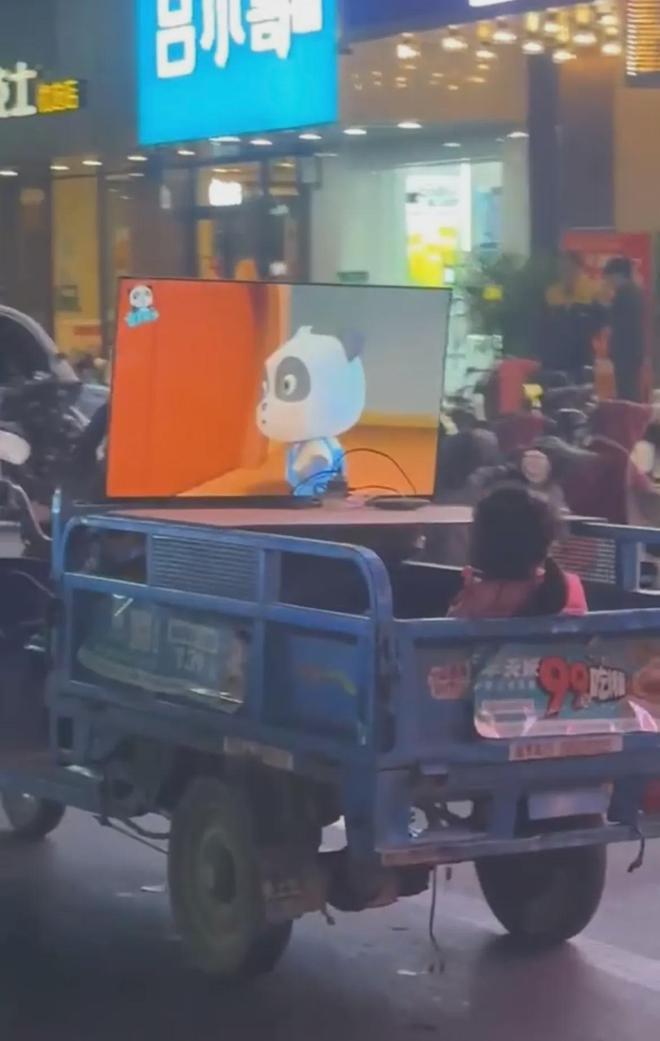 天博官方网站网友拍到有趣一幕女孩坐行驶三轮车斗里看电视：宠溺界的天花板(图1)